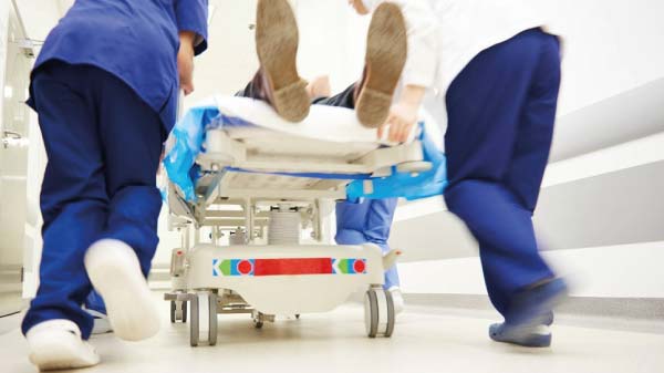 patient-being-pushed-on-hospital-bed-by-two-doctors-wearing-scrubs